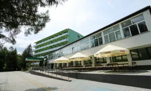 Zielony budynek sanatorium prywatnie, z tarasem i parasolami.