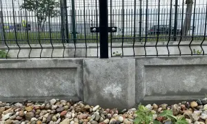 Solidny montaż podmurówki na ceowniku, zabezpieczający teren. Kamienie i beton tworzą trwałą podstawę dla ogrodzenia.