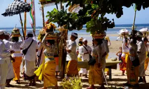Uczestnicy procesji na plaży, niosący kosze z ofiarami, celebrują balijską religię.