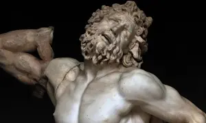 Kamienna rzeźba przedstawia męską postać z rozwianymi włosami i brodą, z wykrzywioną twarzą w bólu lub ekstazie. To dzieło inspirowane stylem Michała Anioła, przypominające antycznego Bachusa.