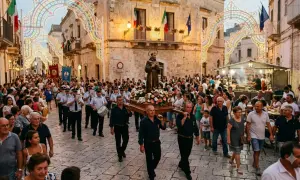 Processione religiosa con statua fiorita, musica e luminarie, un esempio di tradizioni popolari italiane per regione.