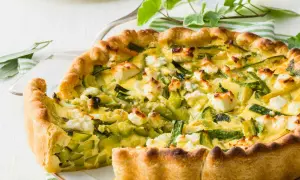 Tarte ricotta courgette dorée, garnie de dés de fromage blanc et de lamelles de courgettes vertes.