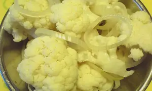 Blumenkohl und Zwiebelringe für blumenkohl sauer einlegen in einer Schüssel.