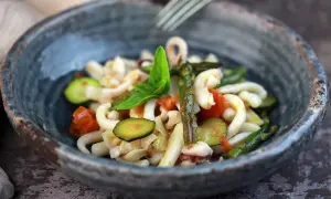 Deliziosa insalata di mare con verdure fresche: calamari, pomodorini, zucchine e asparagi, guarnita con basilico.