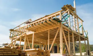 Estructuras de madera para casas en construcción, con vigas y soportes visibles bajo un cielo azul.