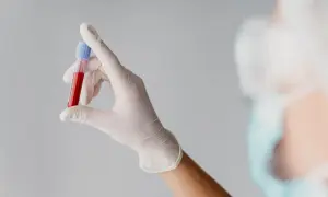 Ręka w białej rękawiczce trzyma probówkę z krwią do badań, np. mchc.