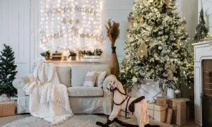 Ideas para decorar mi casa en navidad: árbol nevado, luces cálidas, sofá acogedor, caballito de madera y regalos.
