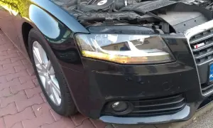 Audi A4 B8 przód: wymiana żarówki kierunkowskazu. Silnik odsłonięty, maska podniesiona.