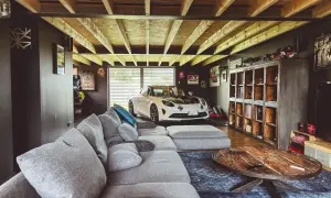 Aménager son garage : un canapé confortable, une voiture de sport blanche et des étagères remplies d'objets de collection.