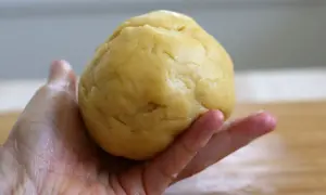 Kruche ciasto do szarlotki w dłoni, gotowe do rozwałkowania. Idealna baza dla pysznego deseru.