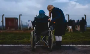 Donna assiste persona in sedia a rotelle, un momento di cura che ricorda l'importanza dell'indennità di accompagnamento dopo i 18 anni.