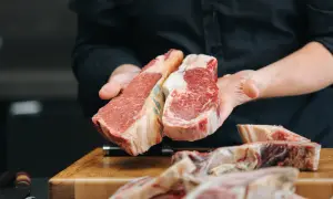 Manos sostienen dos cortes de ternera. La ternera es carne magra, ideal para una comida saludable y deliciosa.
