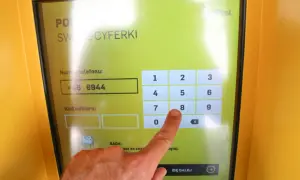 Palec wskazujący naciska cyfrę 8 na ekranie paczkomatu InPost.