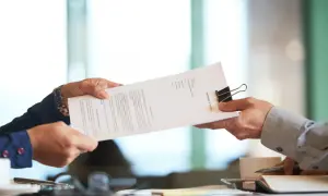 Dwie osoby przekazują sobie dokument "PARTNERSHIP AGREEMENT". To ważny moment, gdy ustalenia stają się faktem.