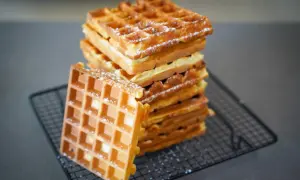 Pile de gaufres dorées saupoudrées de sucre glace, parfaites pour une recette gaufre levure chimique.