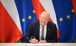 Łysy mężczyzna w garniturze podpisuje dokument na tle flag Polski i UE. Spodziewaj się niespodziewanego, bo nigdy nie wiadomo, co przyniesie przyszłość.