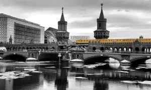 Gelbe U-Bahn fährt über die Oberbaumbrücke in Berlin. Im Vordergrund treibt Eis auf dem Wasser.