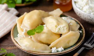 Pyszne pierogi z serem, udekorowane miętą i posypane twarogiem, kuszą swoim domowym wyglądem.