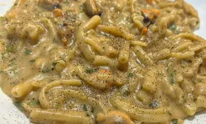 Un piatto cremoso di pasta fagioli e cozze, condito con prezzemolo fresco e pepe nero macinato.
