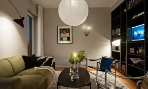 Mysig lounge med en grön soffa, svart soffbord och en bokhylla. Riktat ljus från en vägglampa skapar en varm atmosfär.