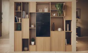 Élégante niche murale en bois clair intégrant un micro-ondes et un four. La largeur micro onde est parfaitement intégrée dans cette composition.