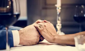 Dłonie splecione na stole, pierścionek na palcu. Romantyczna kolacja, idealna na 8 rocznicę ślubu.