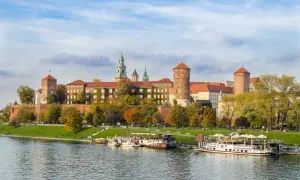 Zabytkowe miasto nad Wisłą, Wawel w jesiennej odsłonie, z łodziami cumującymi przy brzegu.