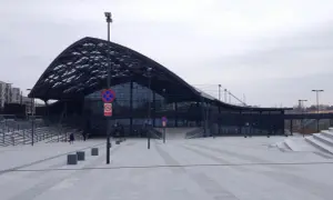 Nowoczesny dworzec fabryczny z charakterystycznym dachem. Przed budynkiem rozległy plac, a obok parking bezpłatny.