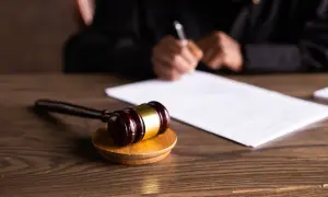 Młotek sędziowski na drewnianym stole, obok dokumenty. Sądowa decyzja o nieważności postępowania kpc zapadnie wkrótce.