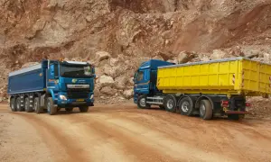 Deux camions bleus, un avec une benne jaune, circulent sur un chemin de carrière. Le prix du km camion 26 tonnes est une donnée clé pour ces transports.