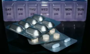 Pigułki w blistrach, w tym Depakine, leżą przed pojemnikiem na leki z podziałem na dni tygodnia.