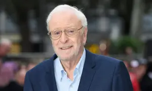 Uśmiechnięty Michael Caine w okularach, ikona kina. Jego niezapomniane role w licznych filmach na zawsze zapisały się w historii.