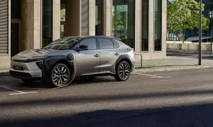En silverfärgad elbil laddas vid en modern byggnad. En fråga som många ställer sig är: vad kostar det att ladda en hybridbil?