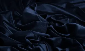 Głęboki, granatowy materiał układa się w miękkie fałdy, tworząc wrażenie aksamitnej głębi.