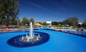Nowoczesny park bajka w Błoniu z fontanną i niebieską nawierzchnią, idealny na letnie zabawy.