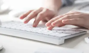 Dłonie piszą na klawiaturze, tworząc tekst. Każde słowo, nawet z twardą spacją, jest starannie wprowadzane.