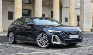 Elegancki, ciemnogranatowy Audi A5 Avant 2025 z charakterystycznym grillem i felgami stoi przed zabytkową budowlą.