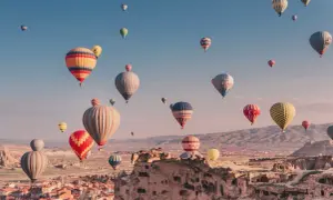 Många färgglada luftballonger svävar över Cappadocias unika landskap i Turkiet. En magisk luftballong turkiet-upplevelse.