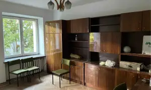 Pokój z meblościanką i oknem, idealny do wynajem mieszkań. Zielone krzesła czekają na lokatorów.