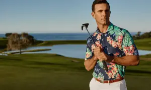 Ein Mann mit einem bunten Polohemd und einem Golfschläger auf einem Golfplatz.