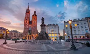 Krakowski rynek główny o zachodzie słońca. Monumentalna Bazylika Mariacka i pomnik Adama Mickiewicza w blasku latarni.