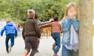 Dzieci biegną, chowając się przed dziewczynką z zakrytymi oczami. To klasyczna zabawa w chowanego, gdzie zasady są proste: kto pierwszy znajdzie ukrytych, ten wygrywa.