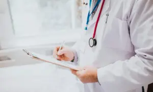 Lekarz w białym fartuchu z dwoma stetoskopami pisze na tablicy.