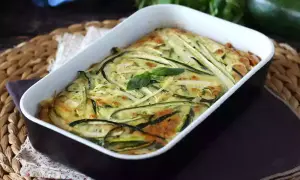 En gyllene frittata i ugn med tunna skivor zucchini och färska örter. En härlig rätt som doftar sommar.