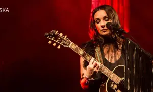 Kasia Kowalska na scenie, grając na gitarze i śpiewając. Jej utwory poruszają serca publiczności.