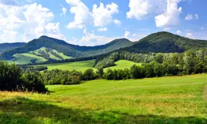 Zielone wzgórza i lasy Beskidu Niskiego pod błękitnym niebem z chmurami. Widok na malownicze **beskid niski szczyty**.