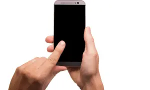 Dłoń trzymająca smartfon z czarnym ekranem, palec wskazujący dotyka ekranu.