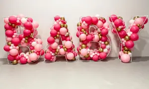 Litery BABY z balonów w odcieniach różu, złota i bieli. Inspiracja, jak zrobić napis na balonie na przyjęcie.