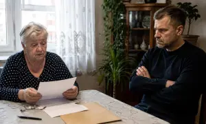 Starsza kobieta czyta dokument, podczas gdy jej syn z założonymi rękami czeka na decyzję. Czy wydziedziczony ma prawo do zachowku?