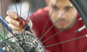 Mężczyzna aplikuje olej na łańcuch rowerowy, dbając o płynną jazdę. To kluczowy krok, by wiedzieć, jak spiąć łańcuch rowerowy i utrzymać go w dobrym stanie.